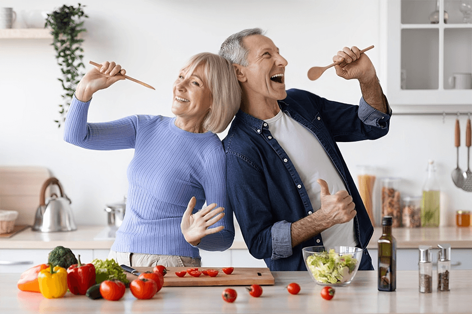 Cheerful mature couple singing and dancing in kitchen.