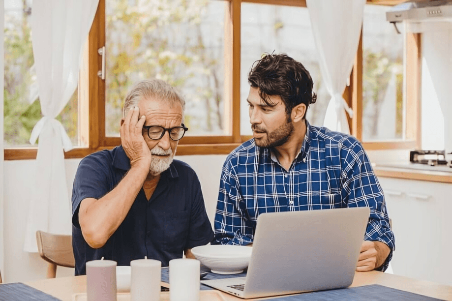Man explaining laptop to older, confused man.