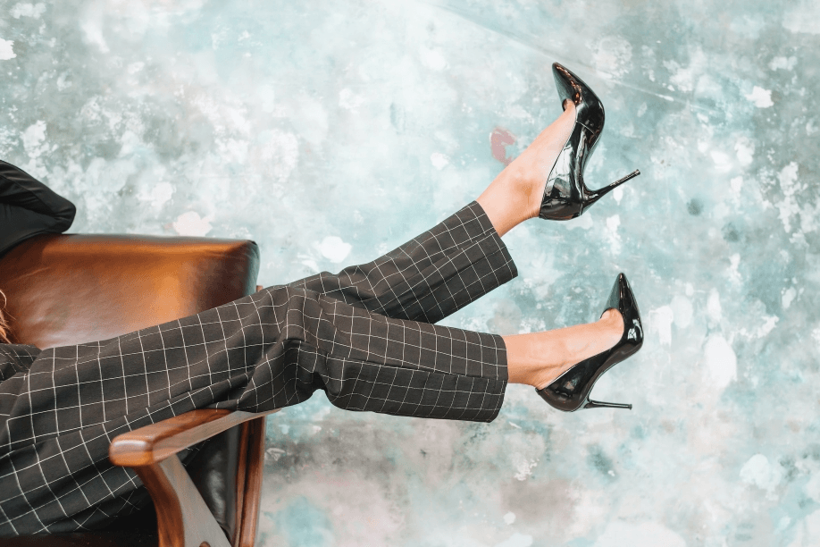 A woman's legs in heels propped up on a chair.