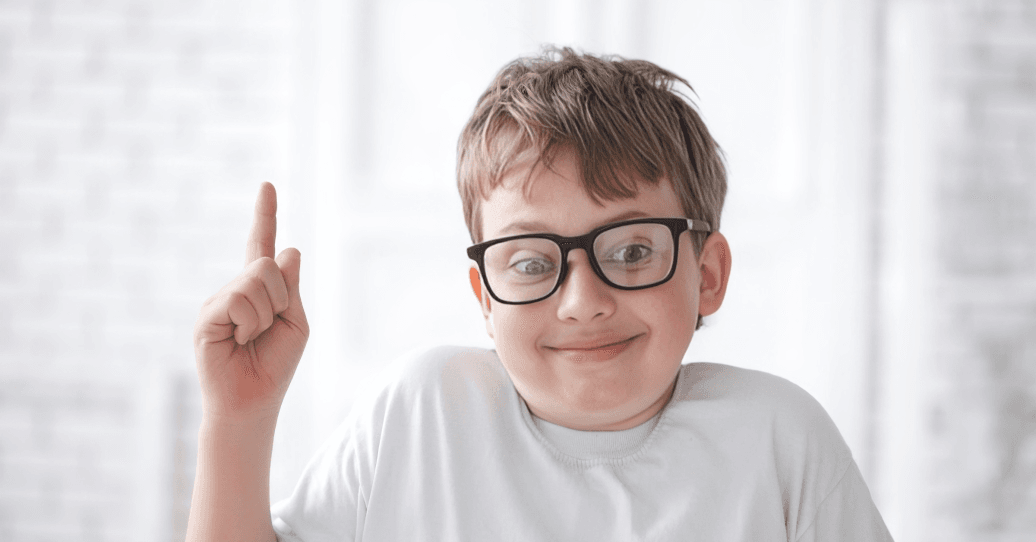 A smiling boy in glasses has an idea.