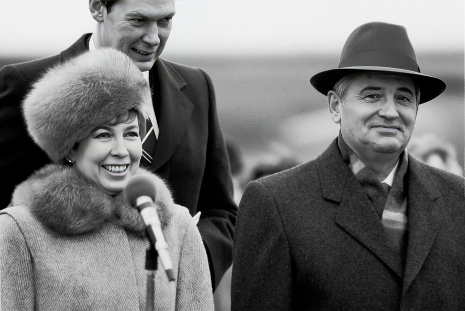 Smiling officials in winter clothing with microphone, during a public outdoor event.