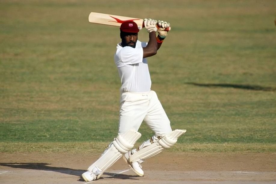 A man holds a bat in his right hand, poised to hit the ball.