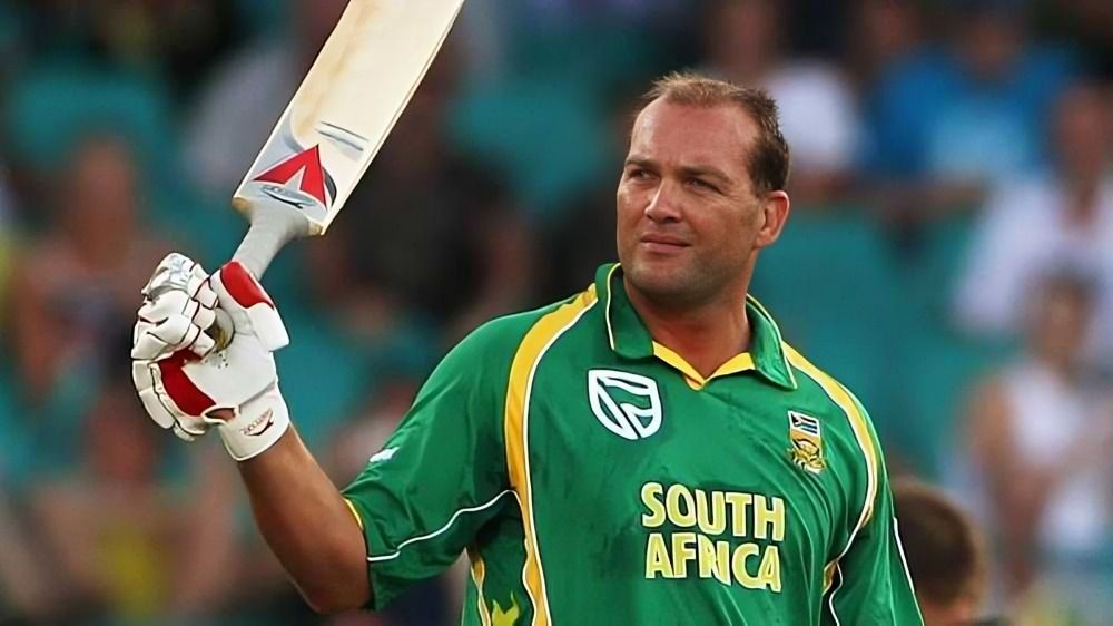 Jacques Kallis is standing in a green uniform, holding a bat in his hand.