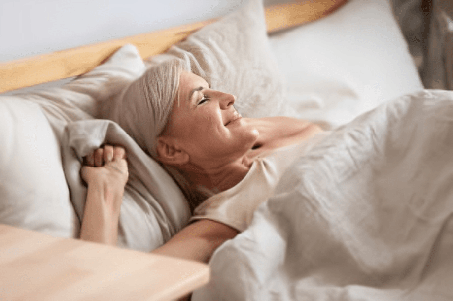 Peaceful senior woman waking up in bed.