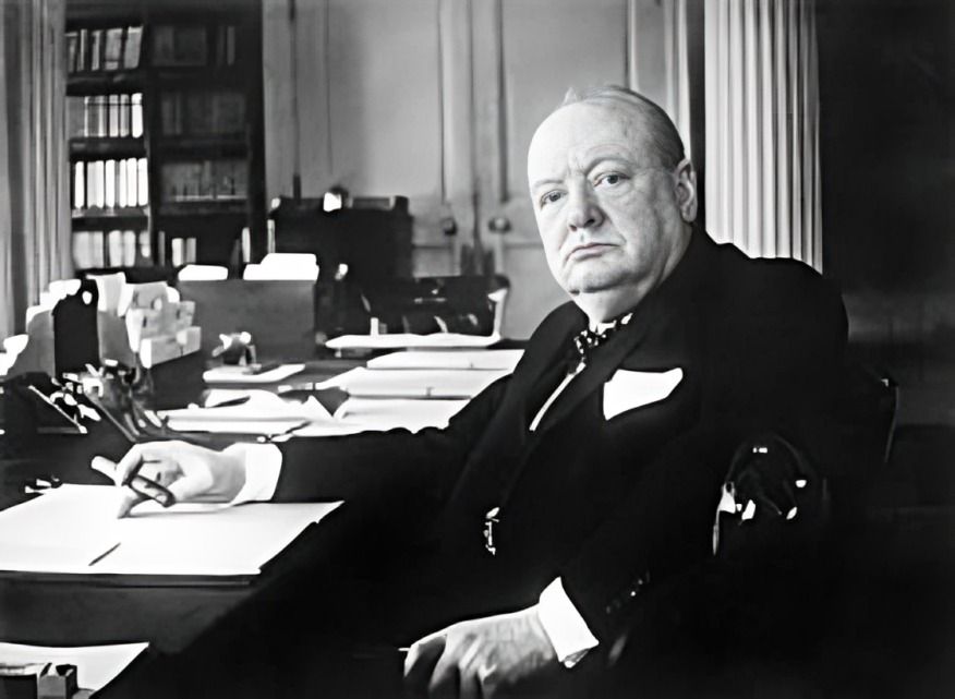 Historic image of Winston Churchill sitting at his desk, deep in thought.