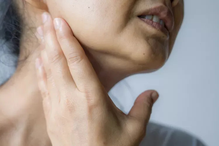 Close-up of a person touching their neck.