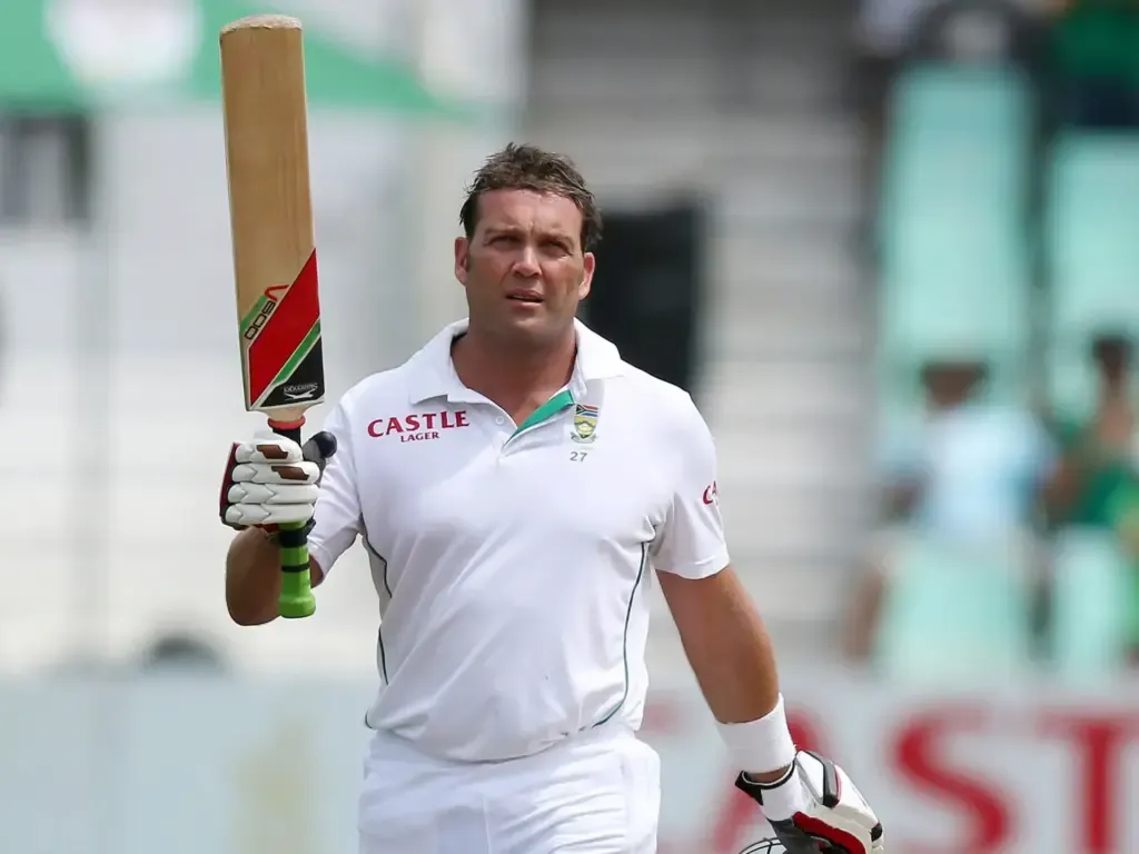 Jacques Kallis is standing in a white uniform, holding a bat in his hand.