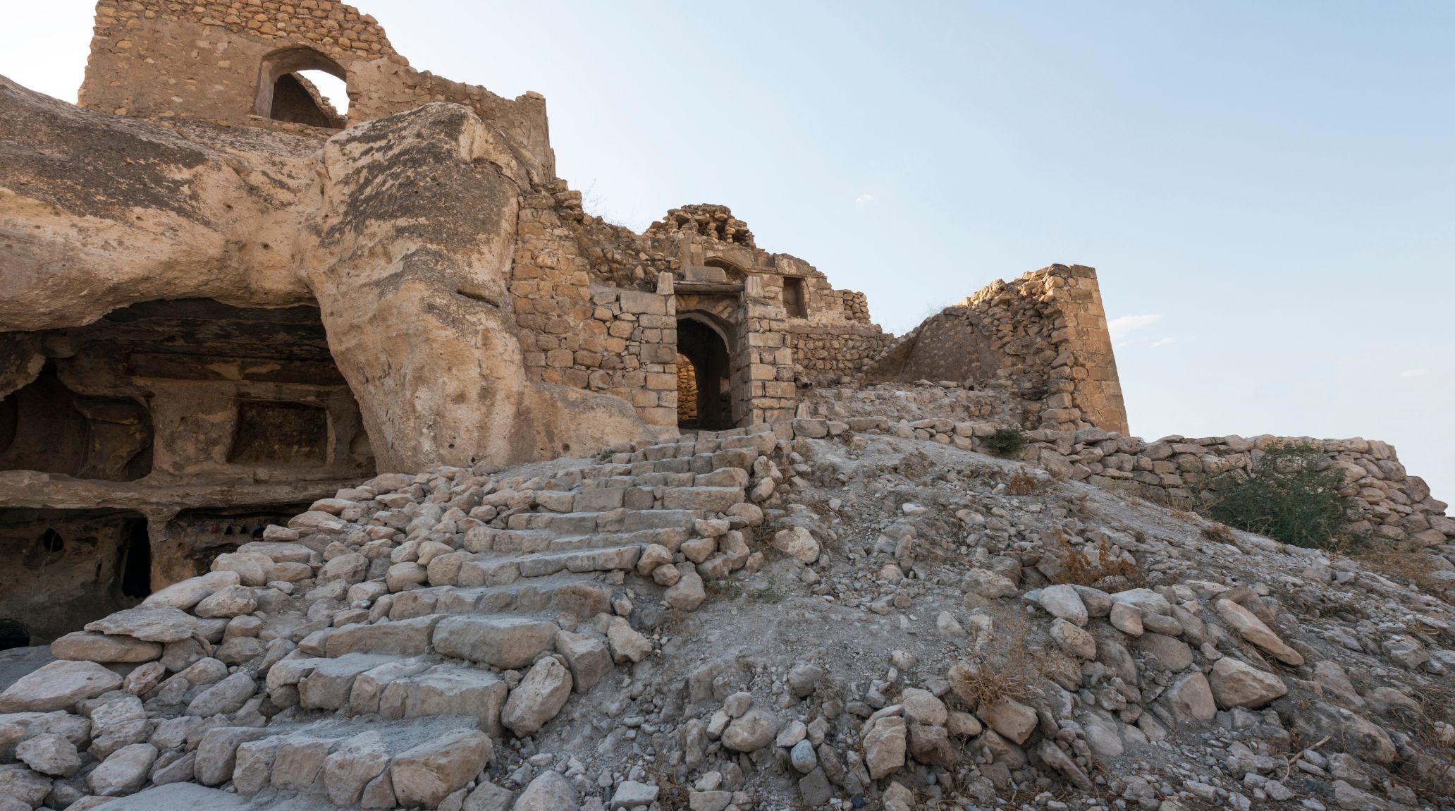 Ancient stone fortress with carved entrance and stairs.
