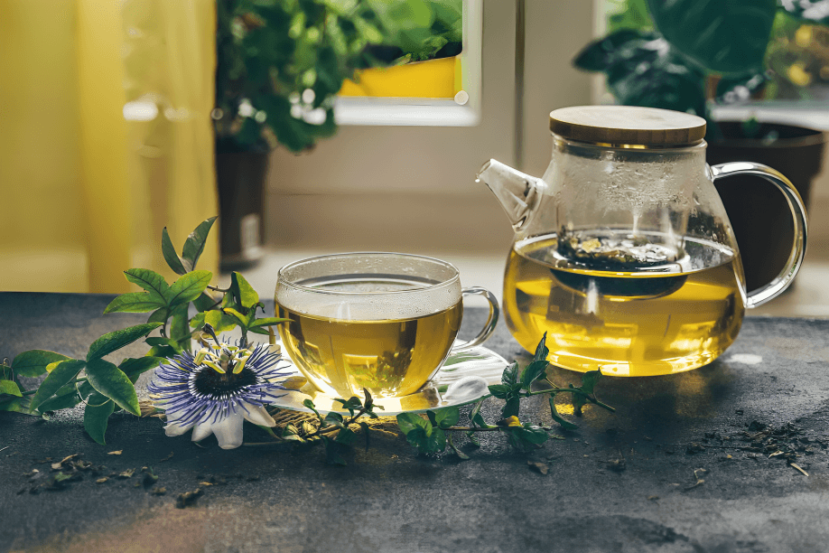 A teapot, teacup, and passion flower on a table.
