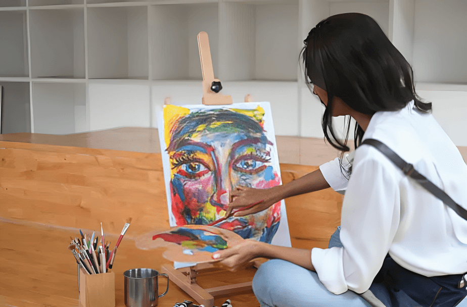 Artist painting colorful portrait on canvas in studio.