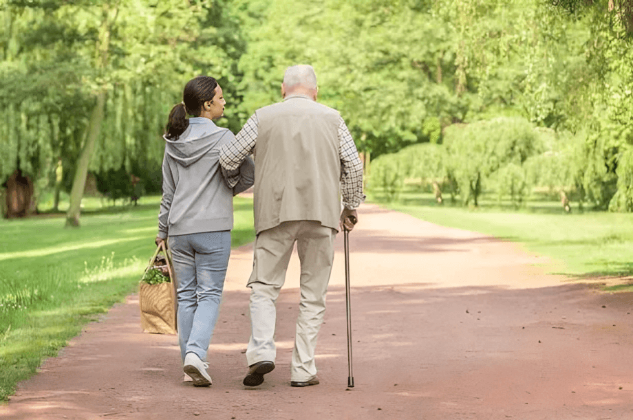Caregiver and senior man walking in park.