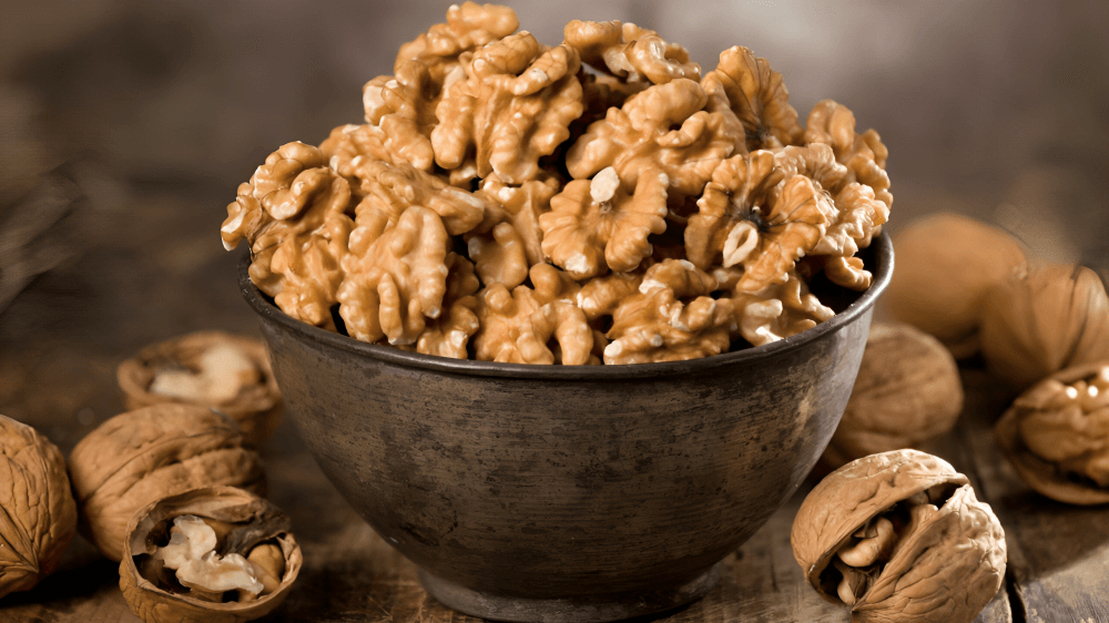 A rustic bowl overflows with shelled walnuts.