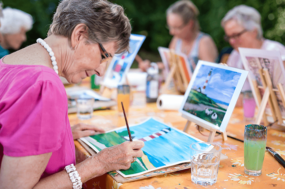 A woman enjoys an outdoor painting class.