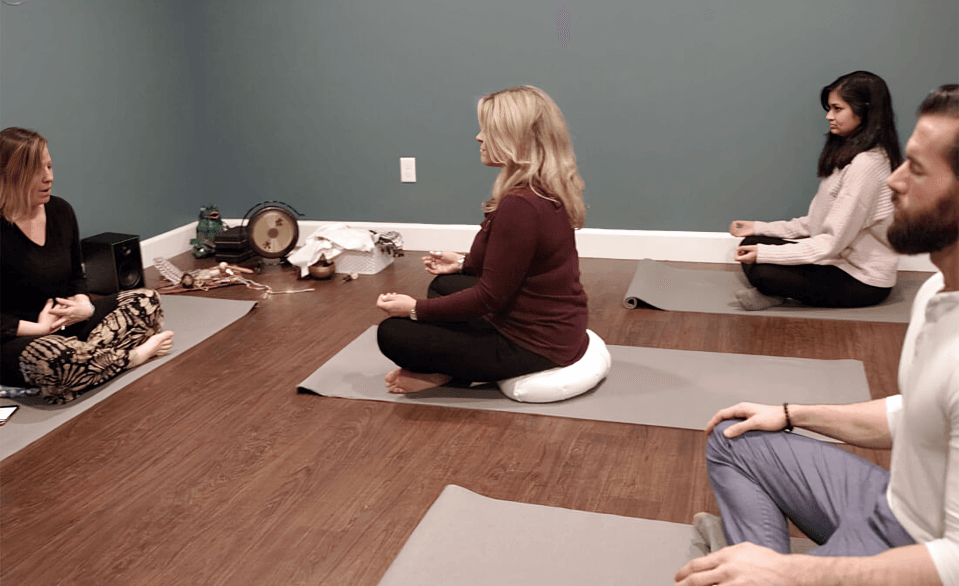 People sitting on mats in a meditation class.