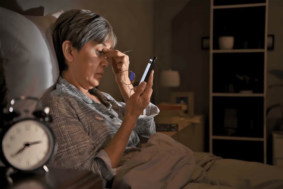A woman in bed checking her phone at night.