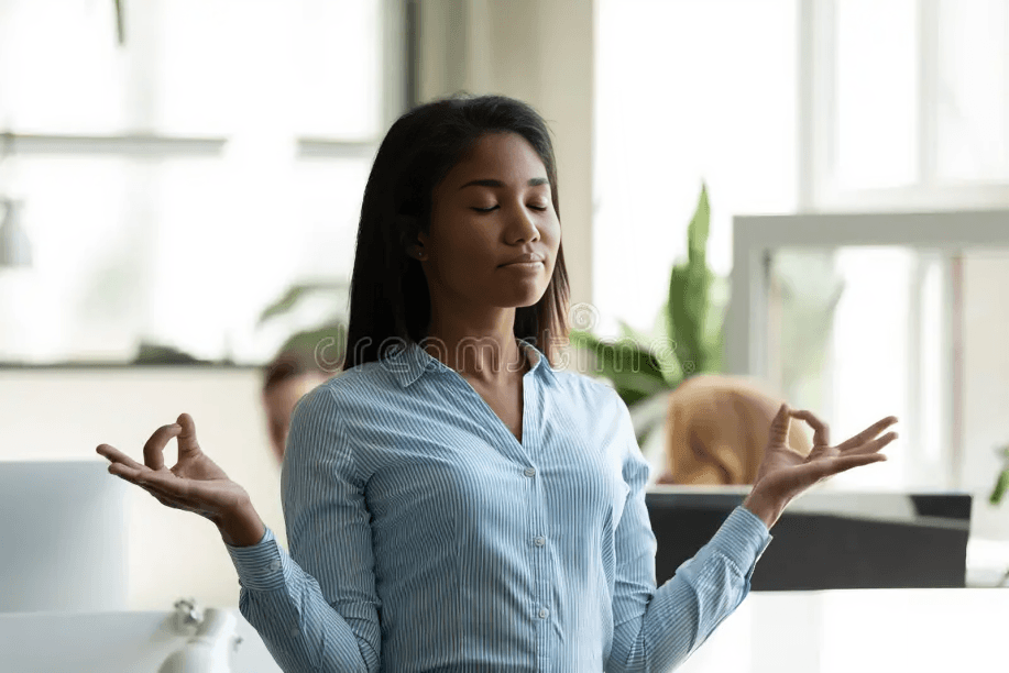 A young woman meditating in an office setting.