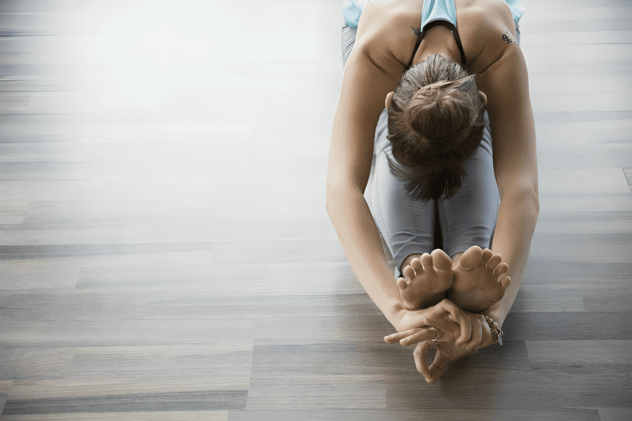 Woman performing a yoga stretch on a wooden floor.