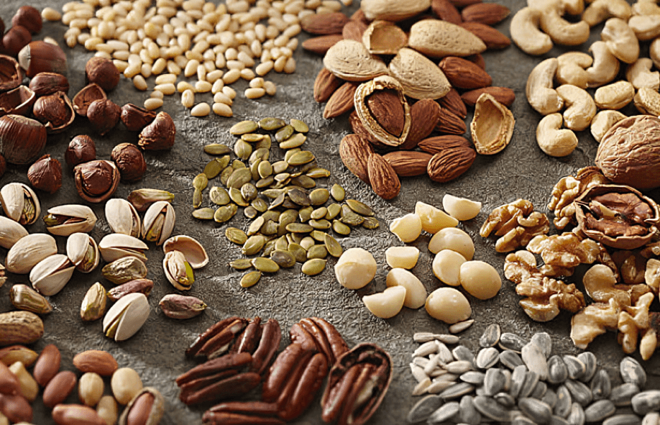 A variety of nuts and seeds arranged on a surface.