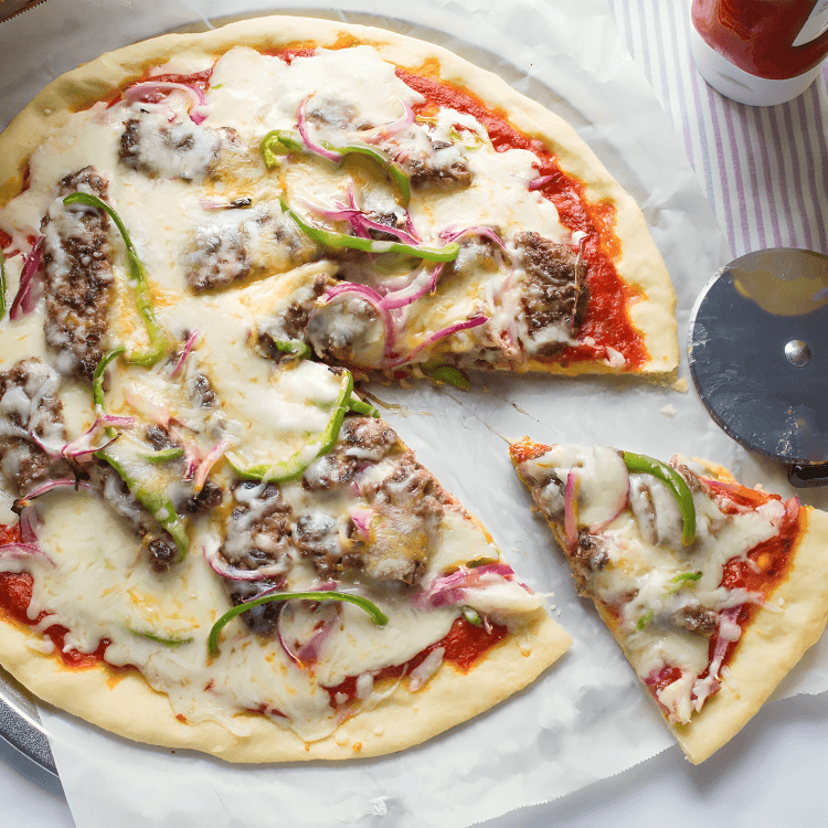 A delicious homemade pizza with meat, cheese, peppers, and onions.