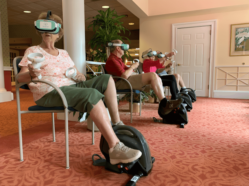 Three seniors use VR headsets while exercising.