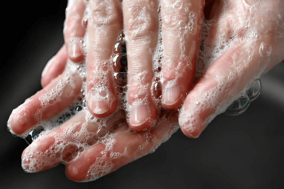 Close-up of soapy hands being washed with water.