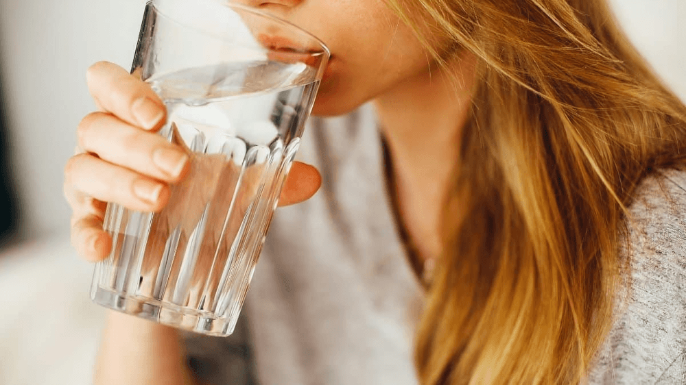 Woman taking a refreshing drink from a glass of water.
