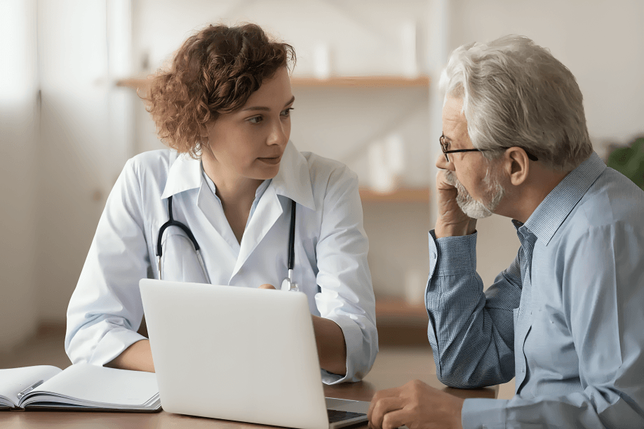 Doctor and senior male patient discussing health at the desk.