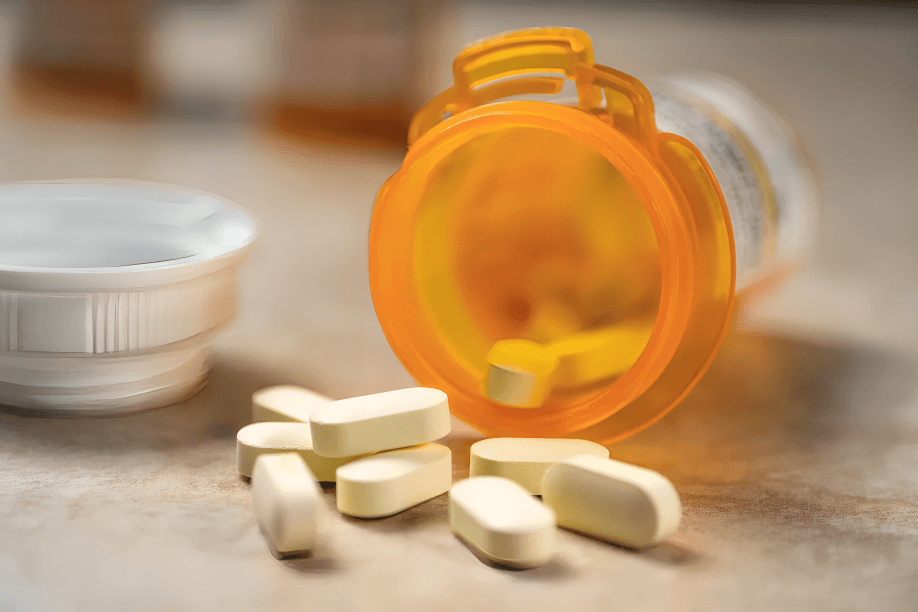 Pills spilled from an orange prescription bottle.