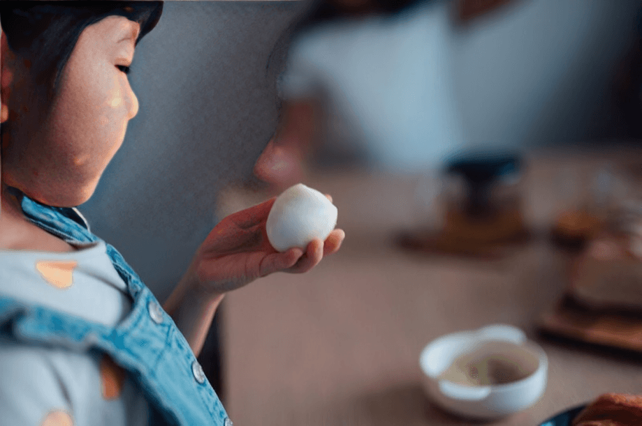 A young child holds a peeled hard-boiled egg.