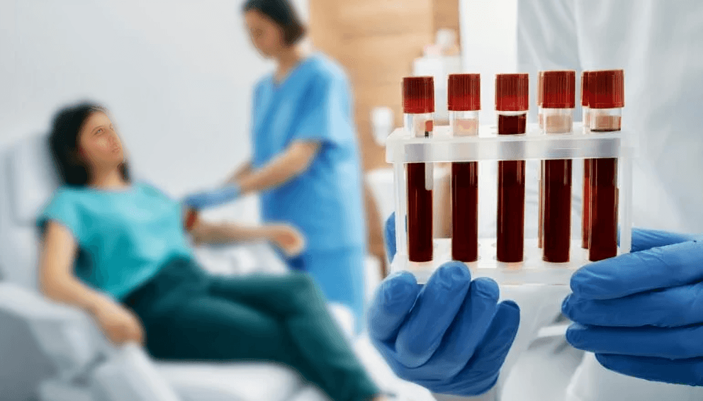 A healthcare professional holding a rack of blood samples.