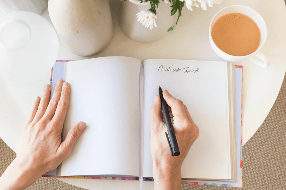 Person writing in an open journal with a pen.