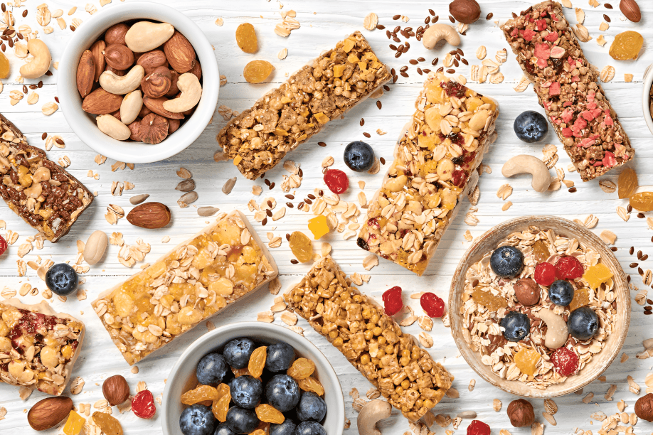 Five granola bars, nuts, and berries on wood.