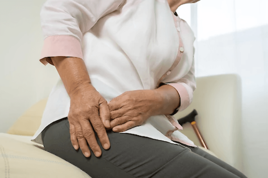 Elderly person holding their hip in pain.