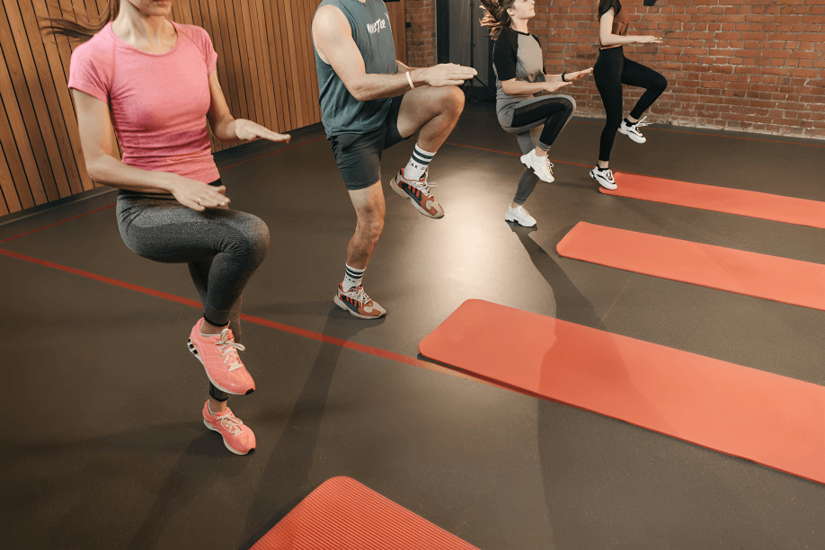 A group of people performing high knees indoors.
