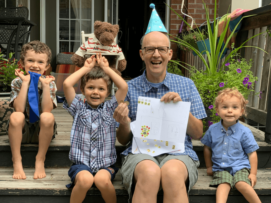 Smiling grandfather and three boys celebrating outdoors.
