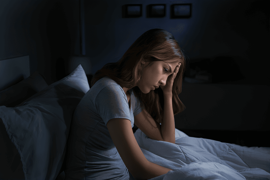 Pensive woman sitting in bed in the dark.