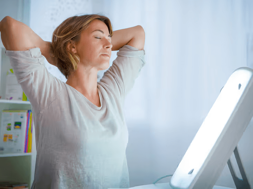 Woman using a light therapy lamp for seasonal affective disorder.