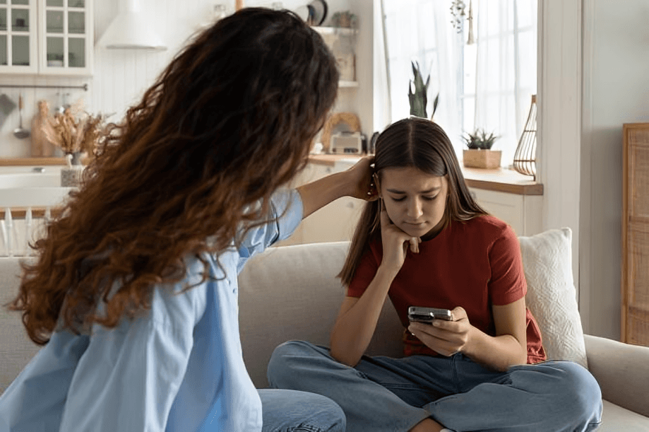 Concerned adult comforting a sad teenager looking at the phone.