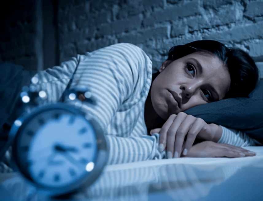 A woman tossing and turning in bed, unable to sleep.