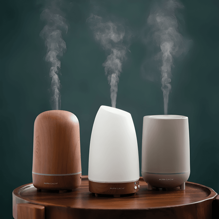Three essential oil diffusers emitting mist on a table.