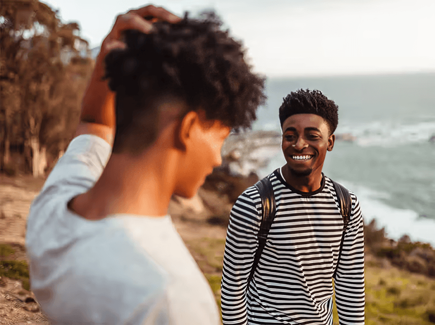 Two young men, possibly African, smiling outdoors.