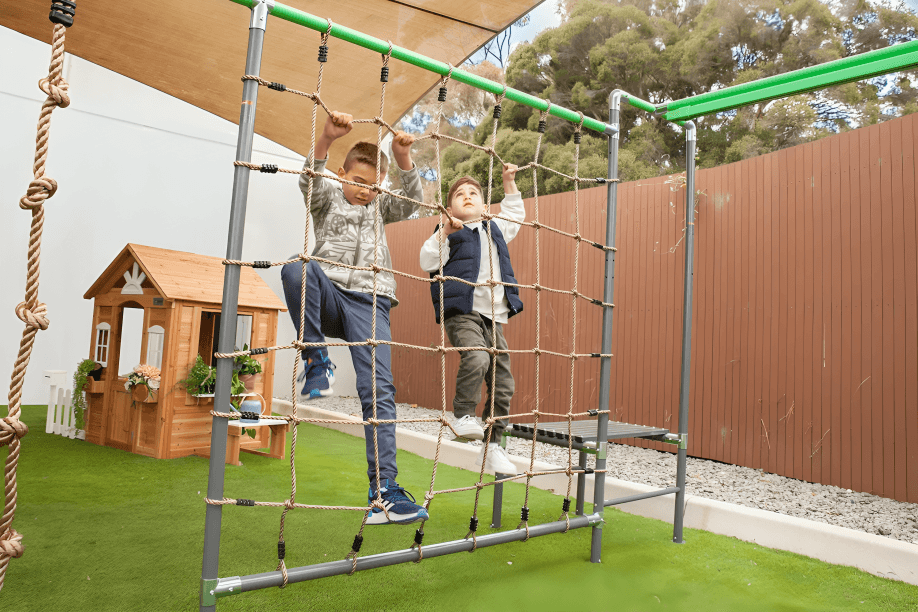 Two boys climbing a rope net on a playground.