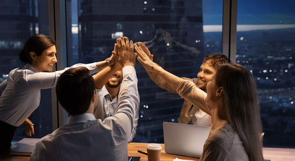 A group of colleagues doing a high-five in the office.