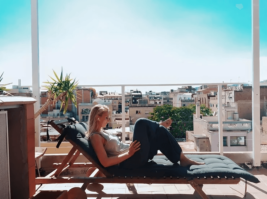 Woman relaxing on a lounge chair on a city rooftop.