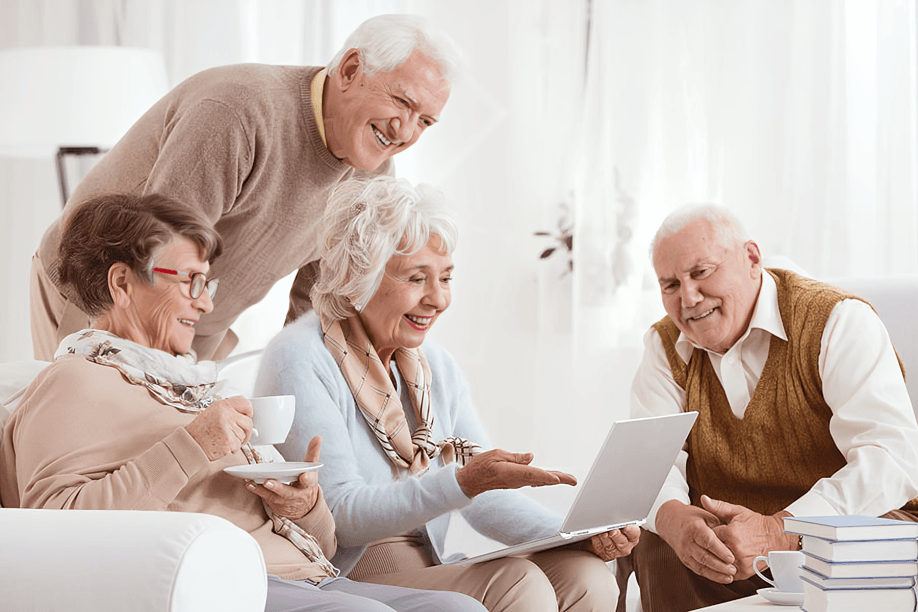 Elders smiling and looking at a laptop together.