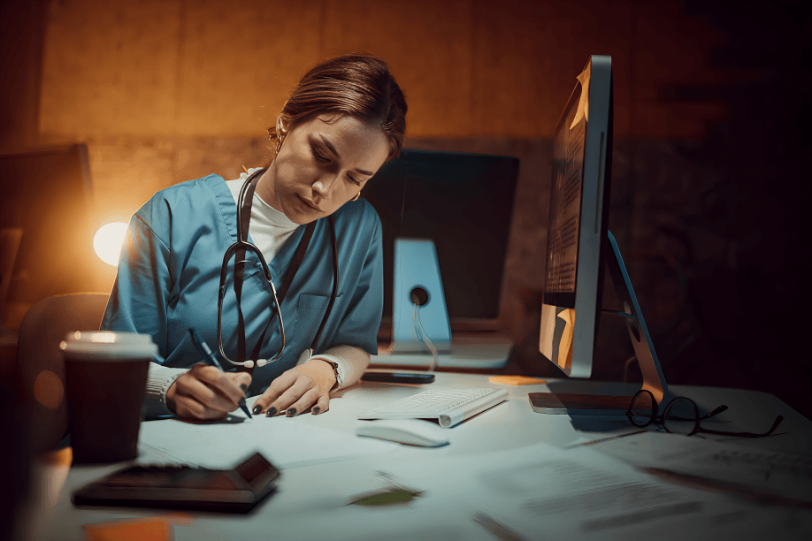 A female doctor works at a desk at night.