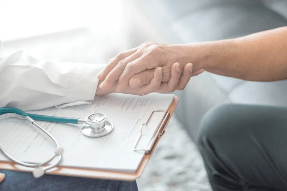 The doctor's comforting hand holding the patient's hand.