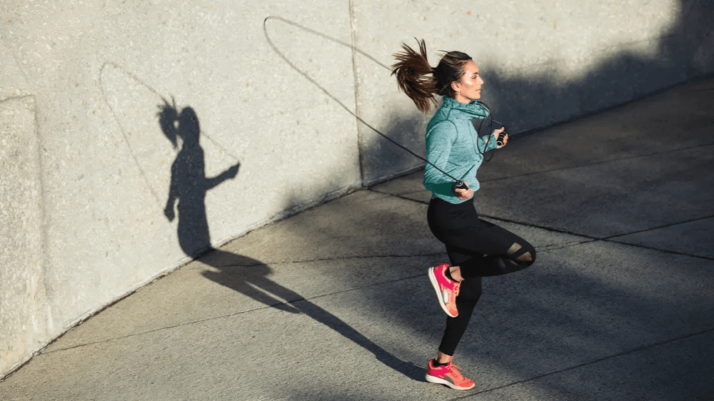 A woman jumping rope with a long shadow.