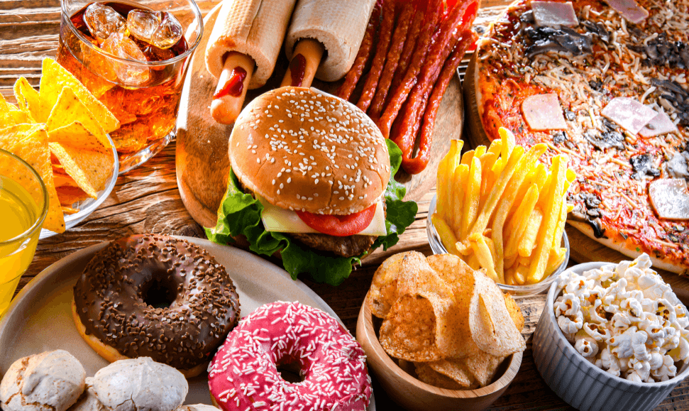 Assortment of unhealthy junk food, including pizza, burgers, fries.