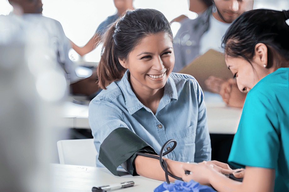 A healthcare professional checks a smiling woman's blood pressure.